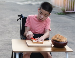 Boy in wheelchair buttering bread