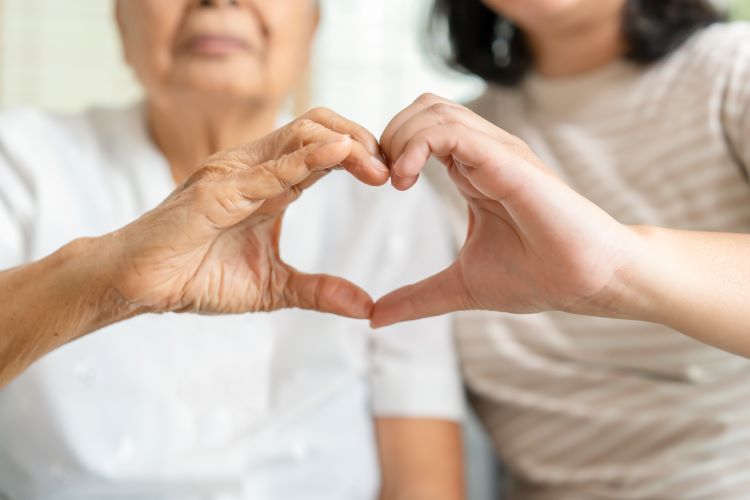 Two ladies creating a heart symbol by joining hands together