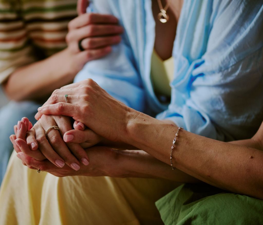 Three people holding hands supportively
