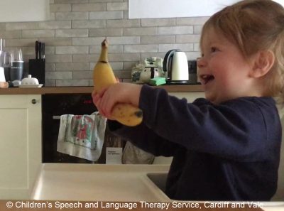 child holding a banana. Copyright Children's Speech and Language Therapy, Cardiff and Vale UHB